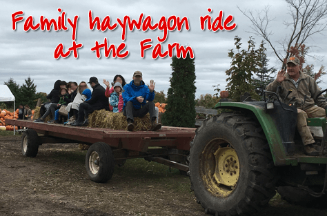 Photo of a happy family heading out for an early Fall hay ride at Fallowfield Tree Farm